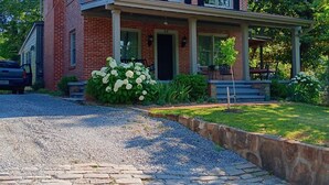 Een huis van baksteen met twee verdiepingen, een voortuin, een grindpad en een verzorgde tuin.