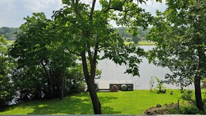 Vista de un lago con un muelle para barcos, abundante vegetación y una zona de césped.