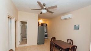 A compact living space with a dining area, kitchenette, and a ceiling fan.