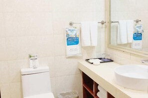 A bathroom with a toilet, a sink, a mirror, and a towel rack with towels. - Xinmei Hotel (Urumqi Hongshan Branch) (Urumqi)
