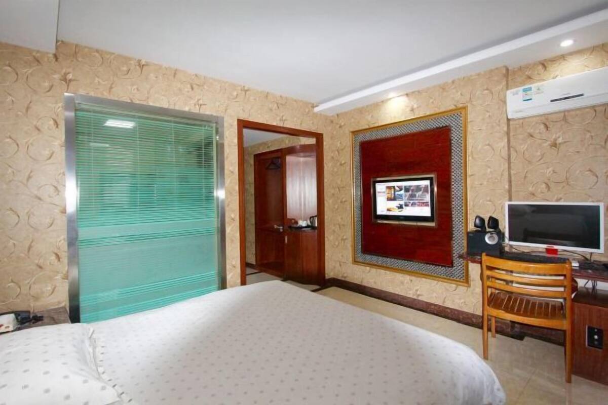 Habitación de hotel con una cama, un escritorio con computadora, televisión y aire acondicionado.