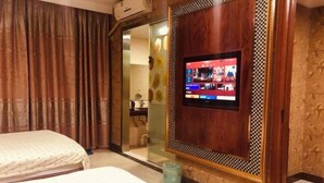 A hotel room with a bed, a television mounted on the wall, and a bathroom visible through a glass door. - Hongdu Hotel (Tongxiang)