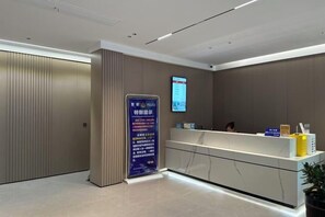 A reception area with a reception desk, a digital screen, and a vertical information board. - Hongdu Hotel (Tongxiang)