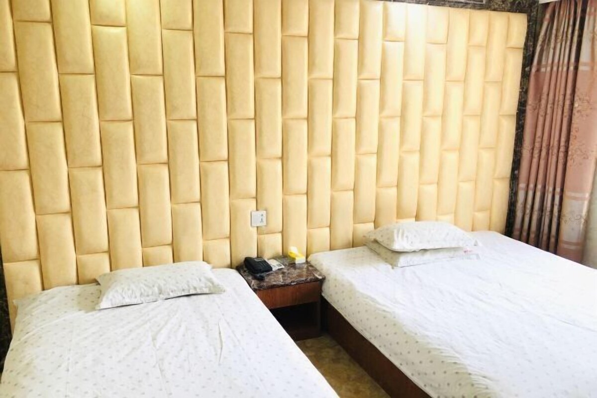 Una camera d'albergo con due letti, una testiera, un comodino e un telefono.