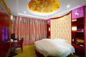 Una camera da letto con un letto, una scrivania con una sedia, un televisore e un'ampia decorazione circolare a soffitto.