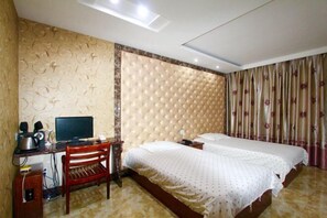 Una camera d'albergo con testiera imbottita, due letti, una scrivania con un computer e una sedia.