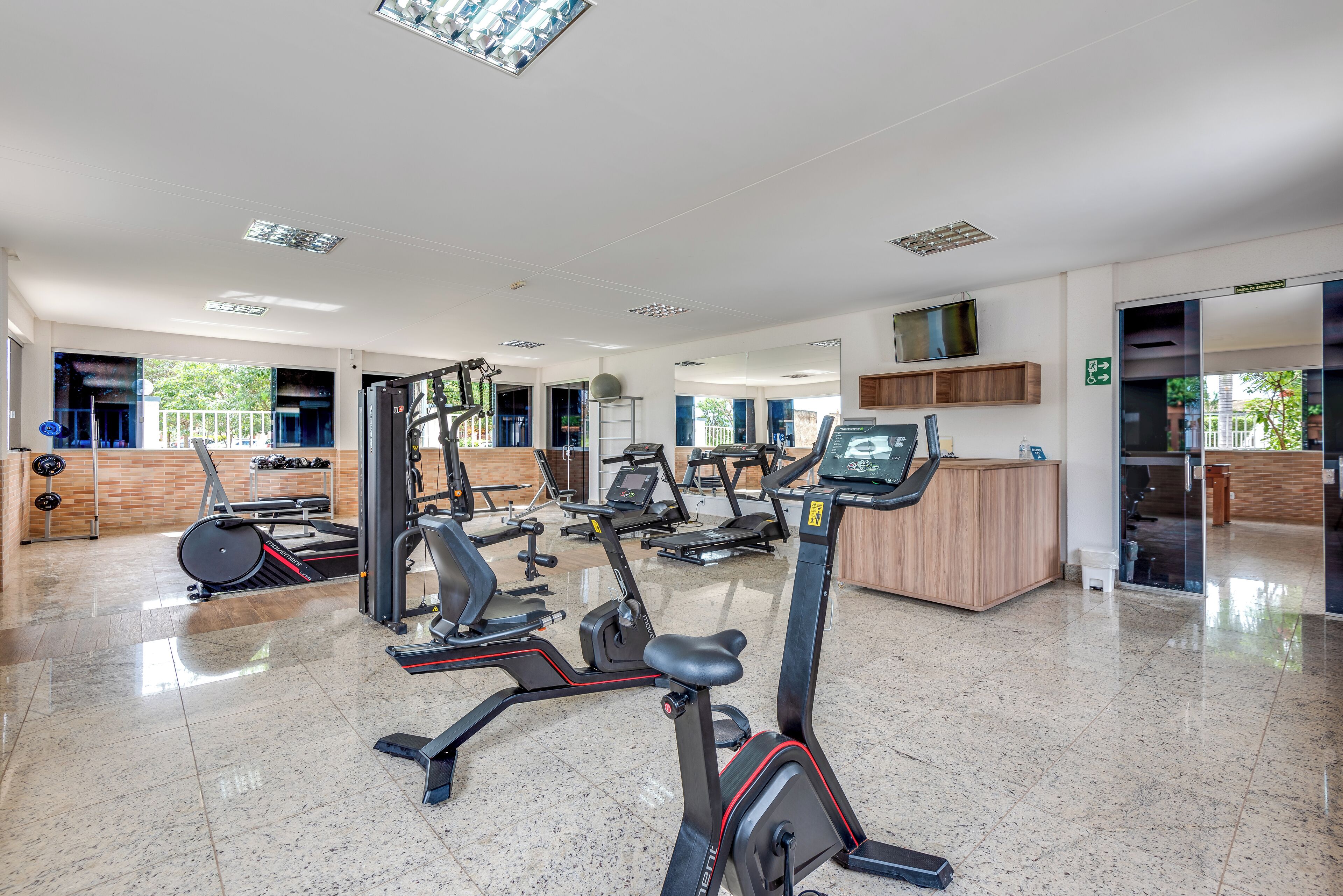 Un gimnasio moderno con distintas máquinas de cardio, un mostrador de recepción y un diseño amplio y ordenado.