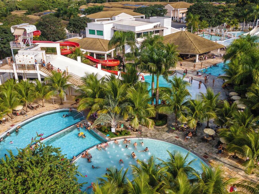 A resort with multiple swimming pools surrounded by palm trees and a water slide.