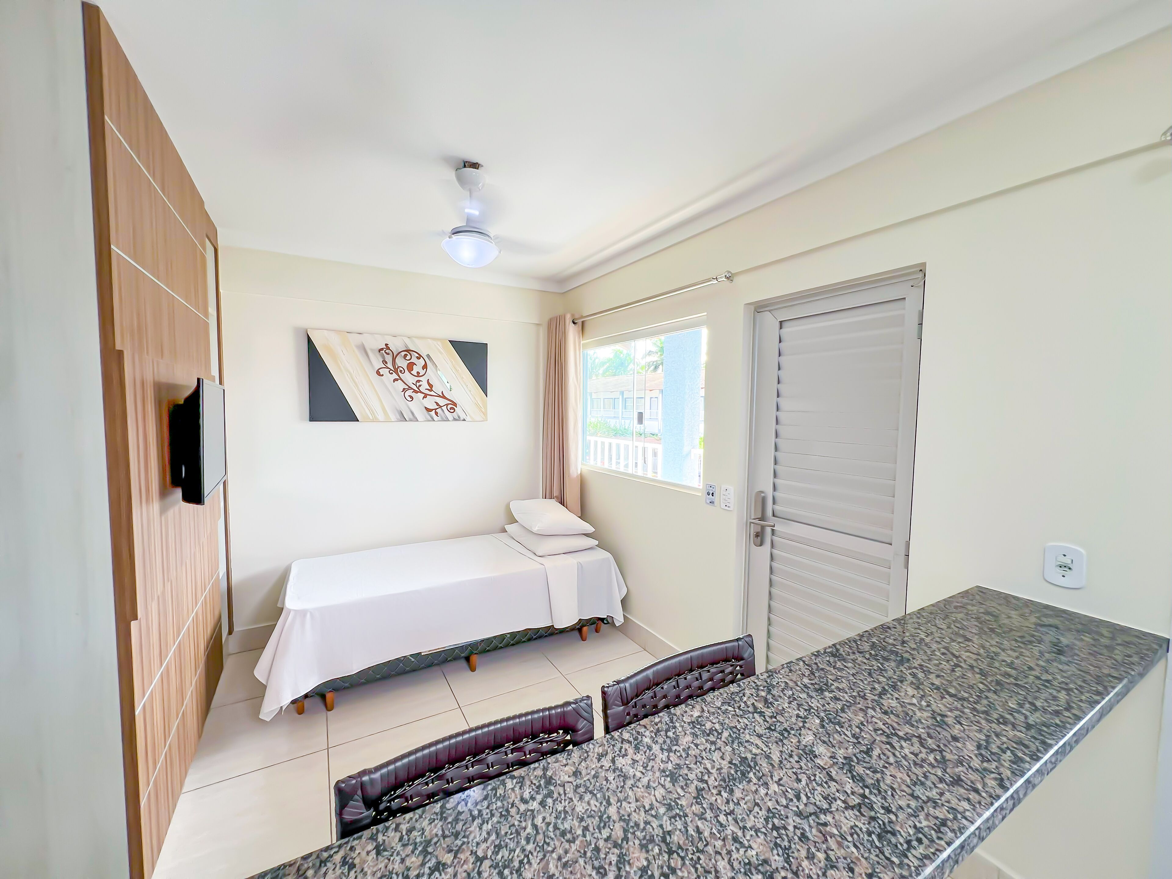 Ein Schlafzimmer mit Bett, Deckenventilator, Fenster und Tür.