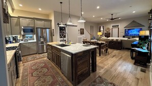 A modern kitchen with a central island, stainless steel appliances, and a dining area with a 'Welcome' sign. - Great Location!  Charming 3-bedroom townhome in brilliant Nashville w/ AC, WiFi (Nashville)