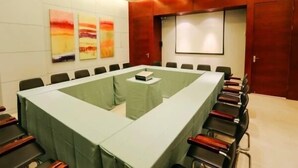 A conference room with a long table, chairs, a projector screen, and abstract paintings on the wall. - Magnotel Xiamen University Shimao Strait Tower Xiamen (Xiamen)