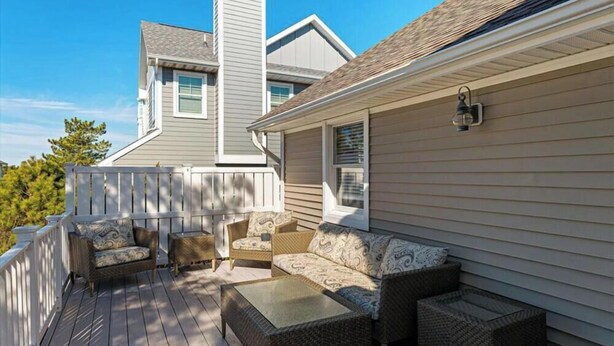 A deck with wicker furniture and a white railing.