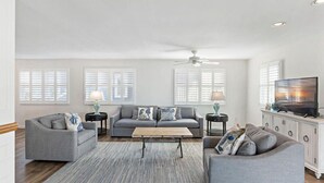 A spacious living room with a grey sofa set, a coffee table, and a television on a cabinet.