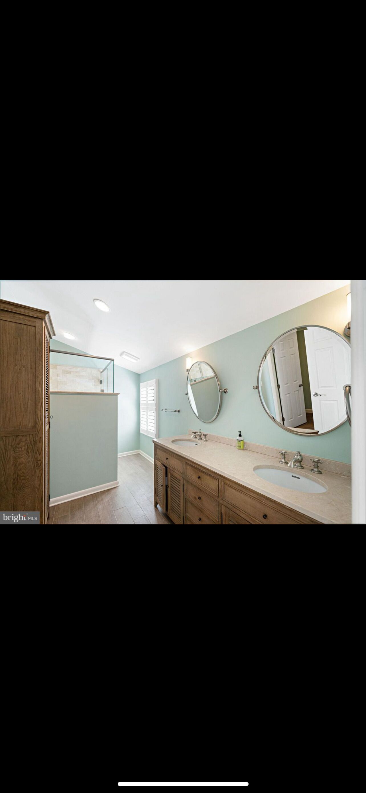 Une salle de bain avec un meuble-lavabo en bois, un évier et deux miroirs fixés au mur.