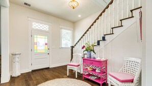 A spacious foyer with a wooden staircase, white walls, and a decorative door with stained glass. - La Onda Azul (Galveston)