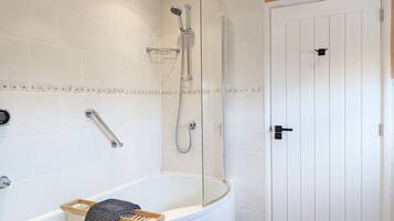 Une salle de bain moderne avec une baignoire sur pieds, une douche à parois de verre et une porte blanche.