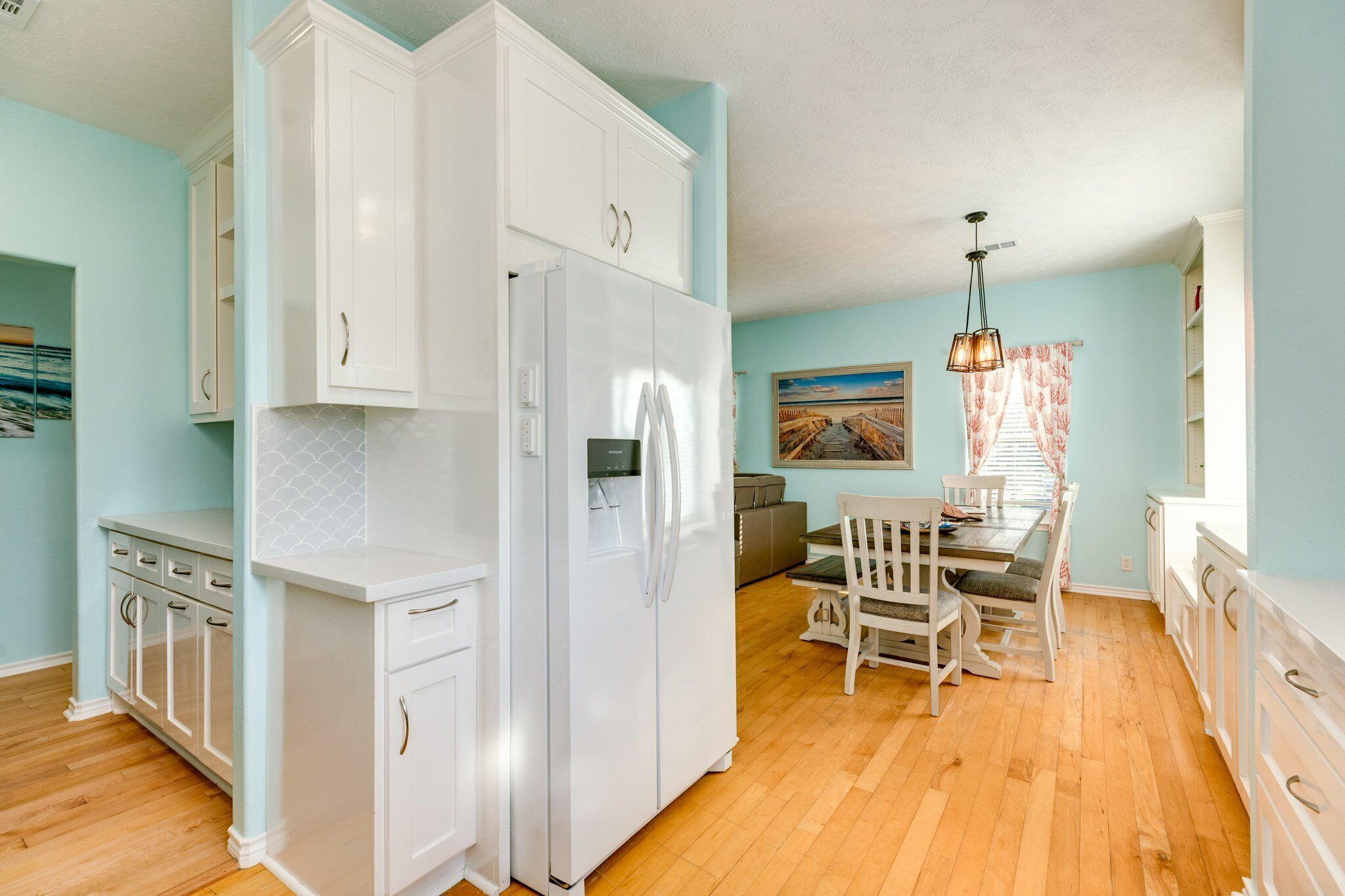 A kitchen with white cabinets, a refrigerator, and a dining area with a table and chairs.