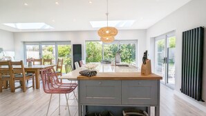 A modern kitchen with a central island, wooden chairs, and a dining table. - A family house that sleeps 6 guests  in 3 bedrooms (West Wittering)