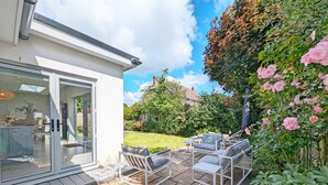 A modern house with a patio area featuring outdoor furniture and a garden. - A family house that sleeps 6 guests  in 3 bedrooms (West Wittering)