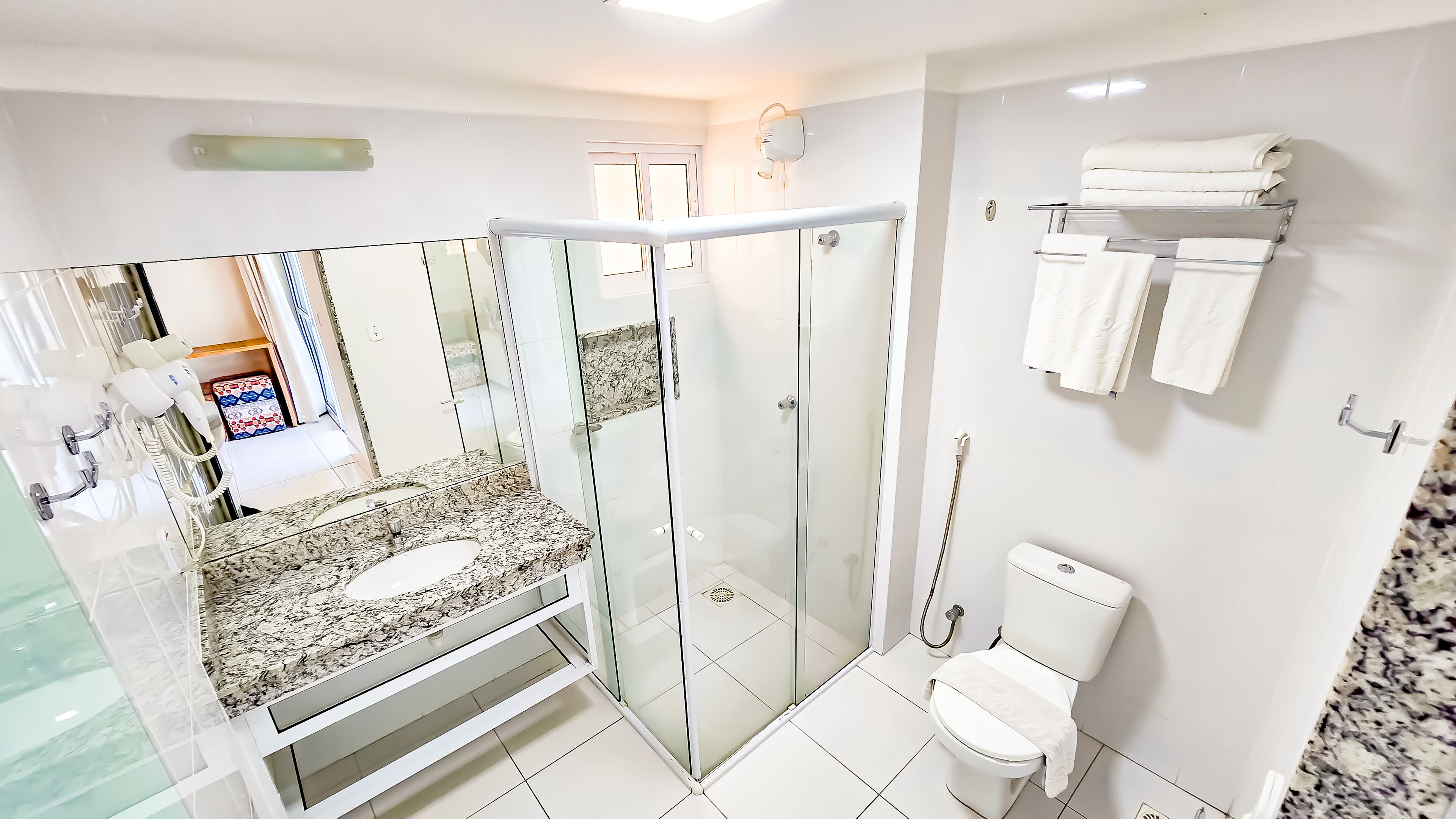 Une salle de bain moderne avec une douche à parois de verre, un lavabo en marbre et des toilettes.