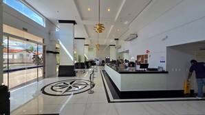 A modern hotel lobby with a reception desk, a large compass floor design, and a view of the outside through large windows. - DiRoma Piazza - Direto com o Grupo DiRoma - acesso ao Acqua Park com café da manhã (Caldas Novas)
