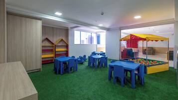 Una sala de juegos para niños con mesas, sillas y una piscina de pelotas.