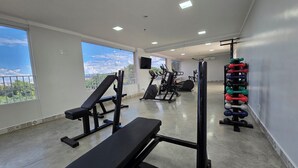 A gym with exercise equipment, large windows, and a view of the outdoors. - DiRoma Piazza - Direto com o Grupo DiRoma - acesso ao Acqua Park com café da manhã (Caldas Novas)