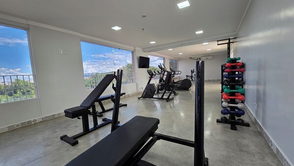 A gym with exercise equipment, large windows, and a view of the outdoors.