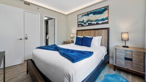 A hotel room with a large bed, a nightstand, a bedside table, and a wall-mounted artwork. - Luxury 2 Suites, Near Parks and Int'l Drive (Orlando)