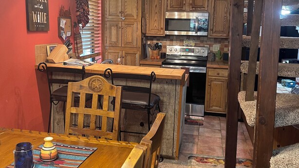 A kitchen with wooden cabinets, a dining table with chairs, and a kitchen island. - Cozy 3 bedroom with loft,  condo in welcoming Angel Fire with WiFi (Angel Fire)