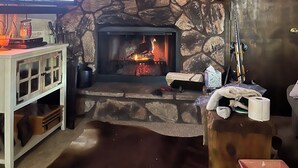 A stone fireplace with a TV displaying a car advertisement, a ski lift sign, and various holiday decorations. - Cozy 3 bedroom with loft,  condo in welcoming Angel Fire with WiFi (Angel Fire)