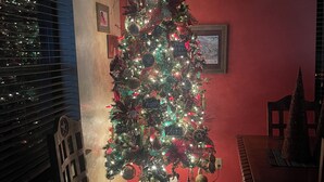 A Christmas tree with ornaments and lights in a room with red walls and a dining table. - Cozy 3 bedroom with loft,  condo in welcoming Angel Fire with WiFi (Angel Fire)