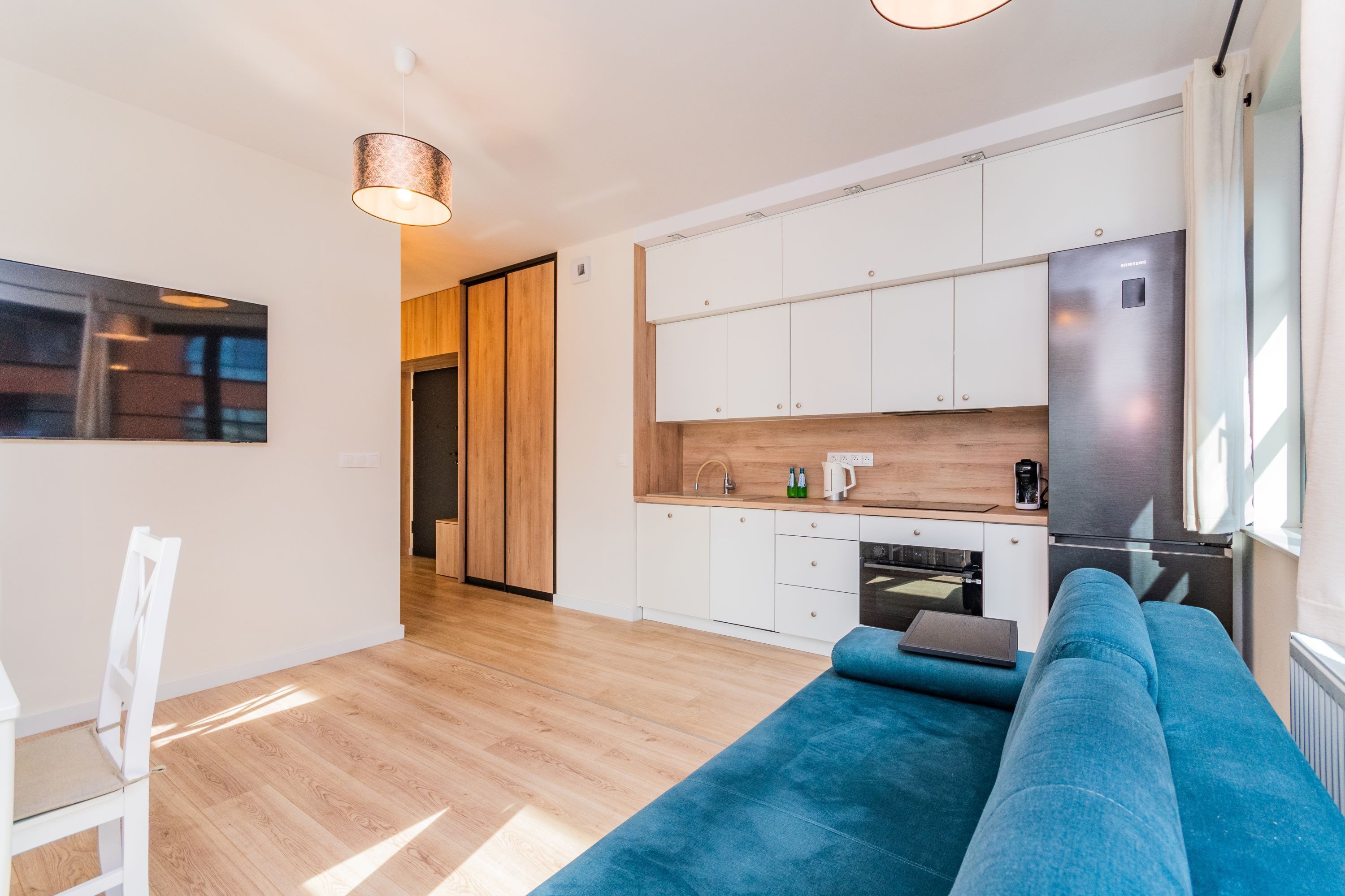 A modern kitchen with white cabinets, a stainless steel refrigerator, and a wooden countertop.