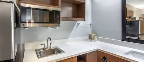 Una cocina moderna con un lavamanos de acero inoxidable, un microondas y armarios de madera.