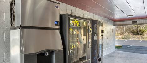 A self-service beverage dispenser with a digital display, a refrigerated beverage cooler, and a vending machine with snacks.