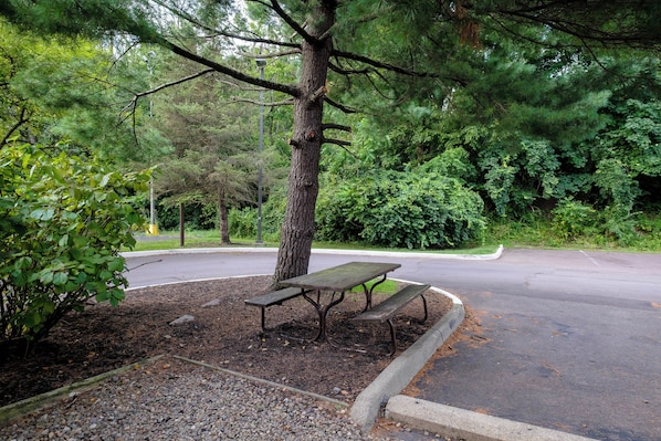 A park bench with a paved path and a road in the background. - HomeTowne Studios by Red Roof Danville, PA (Danville)