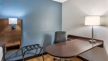 A conference room with a wooden table, a black office chair, a desk lamp, and a wall-mounted light fixture.