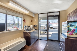A commercial kitchen with a coffee station, a large window, and a view of the parking lot. - HomeTowne Studios by Red Roof Danville, PA (Danville)