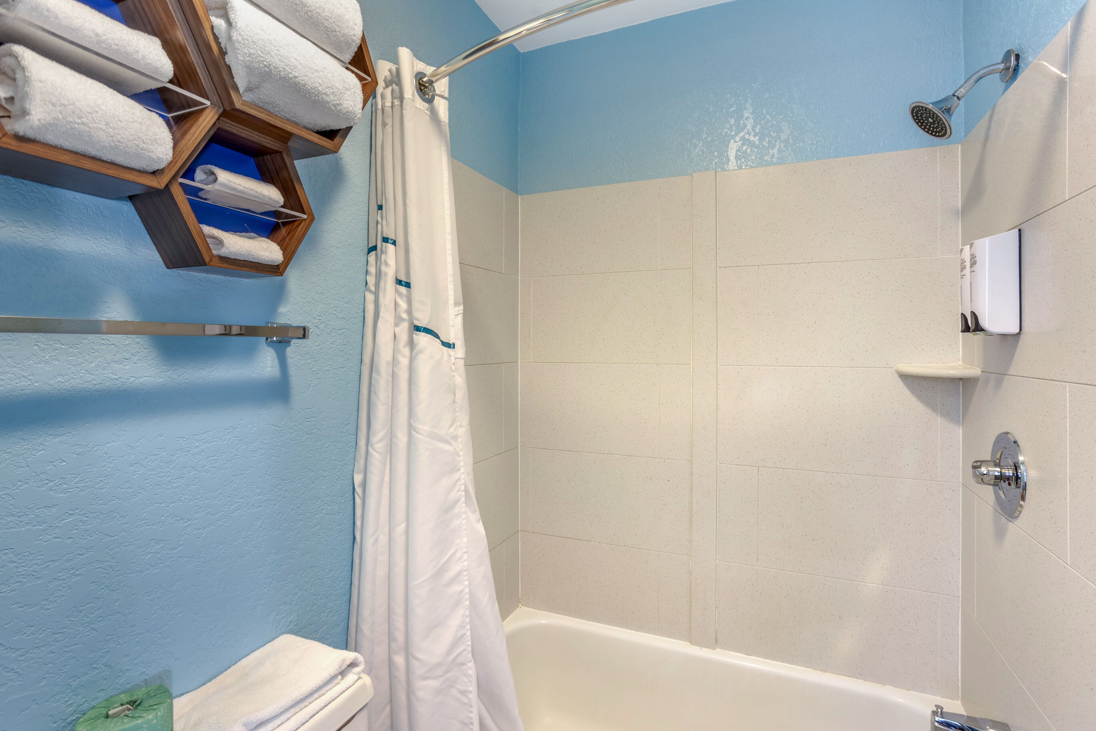 A bathroom with a shower, a toilet, and a towel rack with towels.