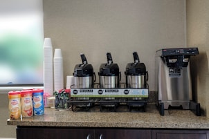 Una estación de café con tres cafeteras Bunn, un dispensador de agua y diversas opciones de leche para café.