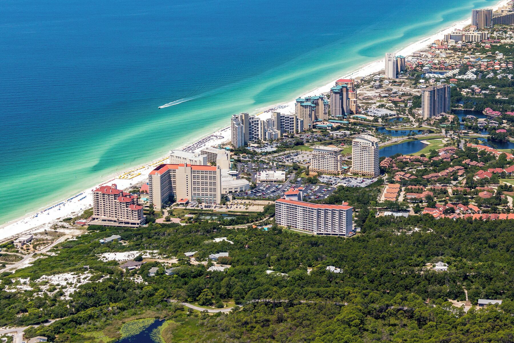Eine Luftaufnahme einer Küstenstadt mit Hochhäusern, einem Strand und einem Golfplatz.