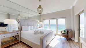 Une chambre spacieuse avec un grand lit, une coiffeuse avec un miroir et une vue sur l’océan.