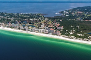 Ett flygbildsbild av en kuststad med en strandpromenad, höga hotell och en blandning av bostads- och affärsbyggnader.