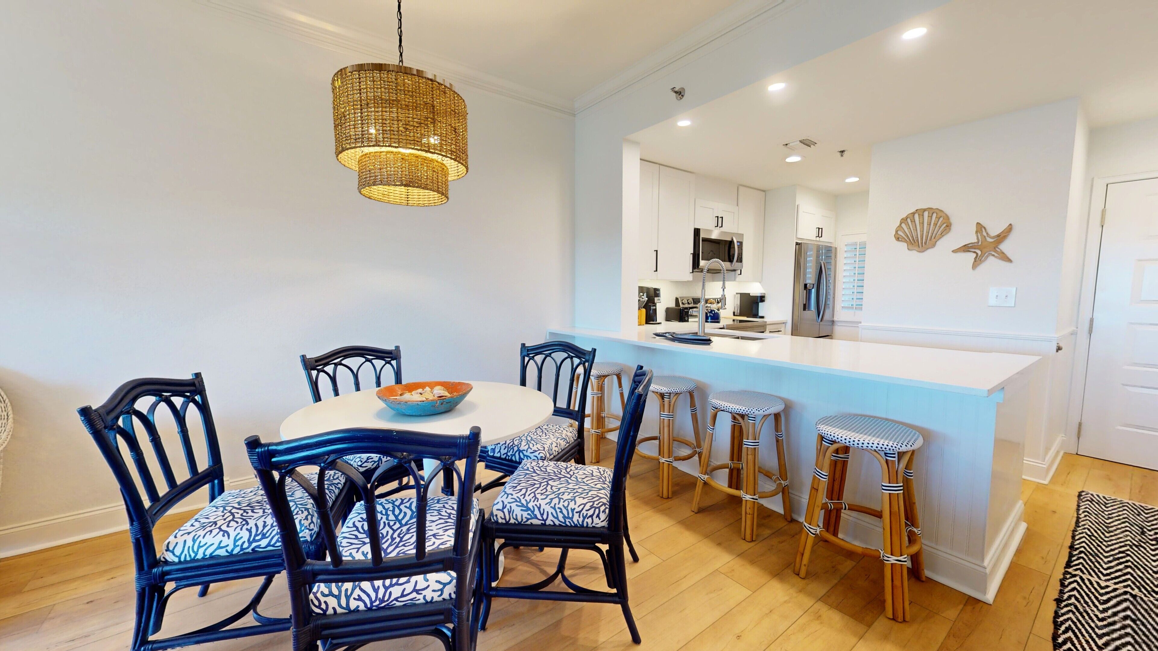 A dining area with a round table, six chairs, and a central island with stools.