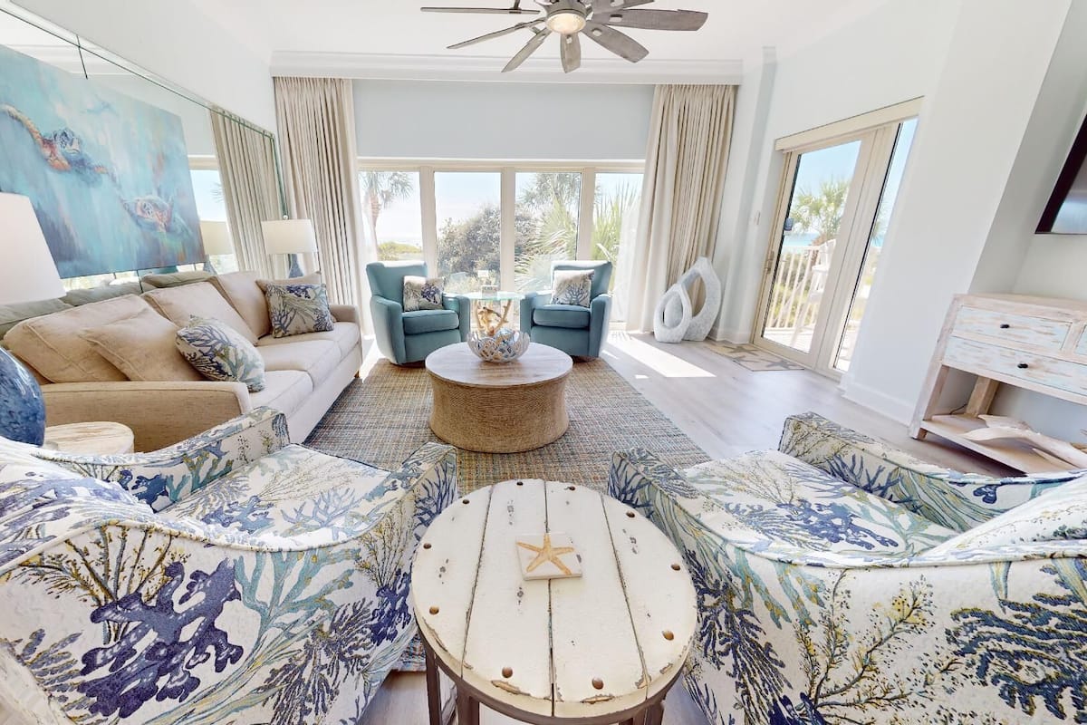 A spacious living room with a large window, a ceiling fan, and a view of the outdoors.