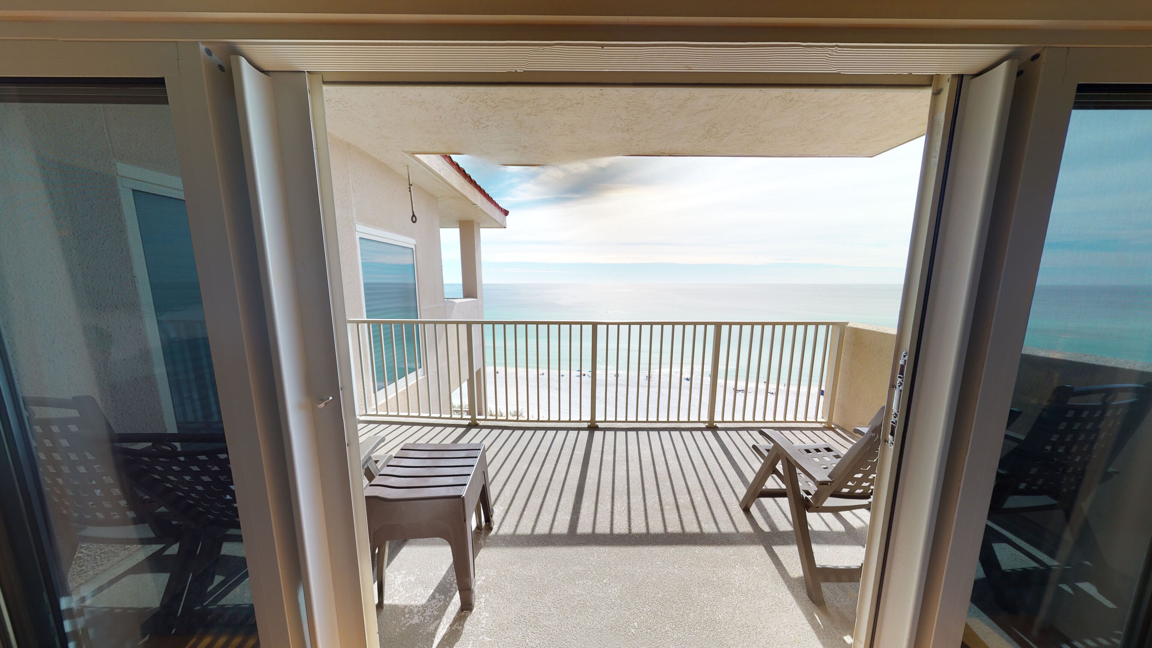 A balcony with a view of the beach and ocean.
