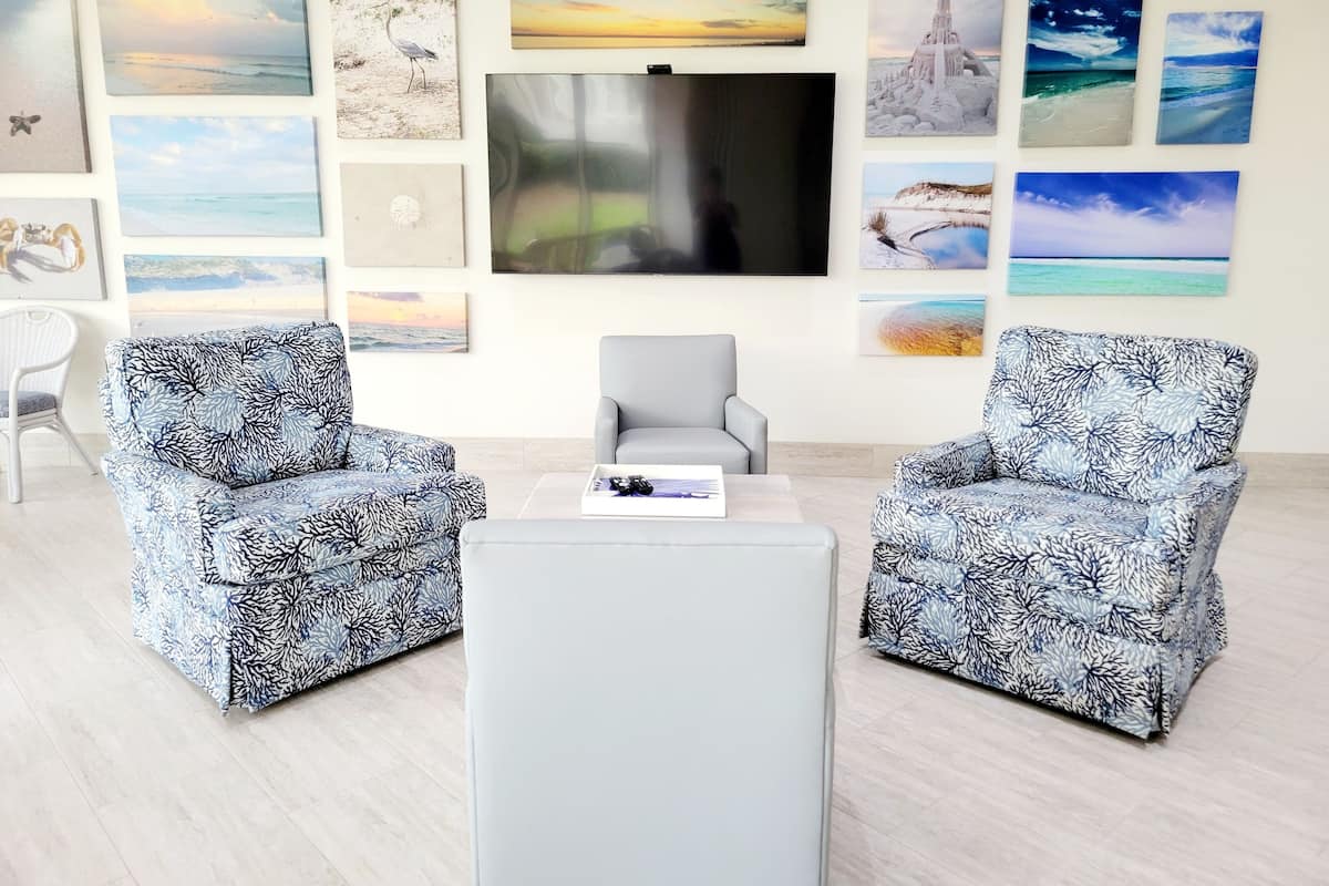 A living room with two patterned armchairs, a coffee table, and a flat-screen TV mounted on the wall.