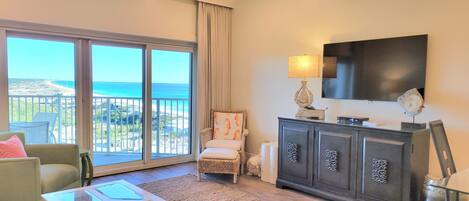 A spacious living room with a large balcony, a flat-screen TV, and a modern fireplace.