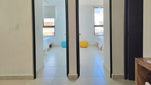Ein Flur mit zwei zur Schlafzimmern führenden Türen, jedes Zimmer mit einem Bett und einem Fenster.