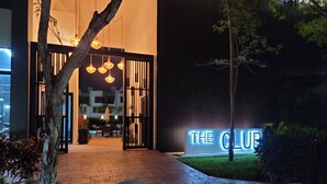 Ein Gebäudeeingang bei Nacht, mit einem Schild, auf dem 'THE CLUB' steht.